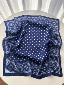 Detailed close-up of navy blue polka dot silk scarf with elegant geometric border