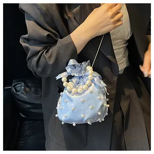 Detail der hellblauen Satin-Beuteltasche mit weißen Perlen und Seidenbandschleife