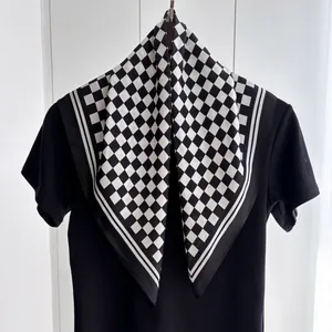 Close-up of black and white checkerboard silk scarf draped on a black t-shirt