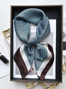 Dettaglio di foulard in seta con anelli geometrici blu e bordo marrone su un vassoio