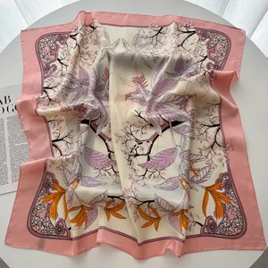 Elegante foulard quadrato in seta con motivi floreali e bordo rosa su un tavolo