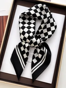 Close-up of black and white checkerboard silk scarf folded elegantly in a gift box