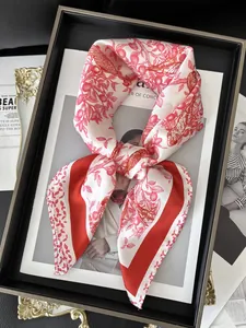 Macro view of red floral silk scarf with bird prints and elegant red border detail