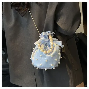 Detail der hellblauen Satin-Beuteltasche mit Perlen, Kordelzug und Kettenriemen
