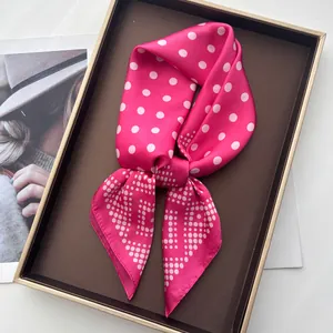 Close-up of pink polka dot silk scarf in a premium gift box with luxury aesthetic