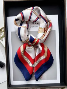 Dettaglio di un foulard in satin con motivi a catena e cinture piegato a forma di fiocco