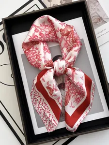 Close-up of floral silk scarf with red bird patterns on a stylish magazine background