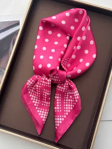 Detailed view of pink satin scarf with white polka dots placed in a luxury gift box