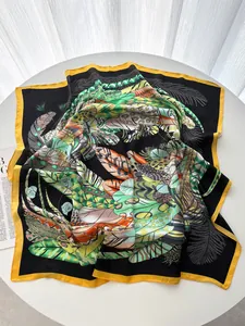 Detail of leaf and feather print silk scarf with black base and yellow hem on white table