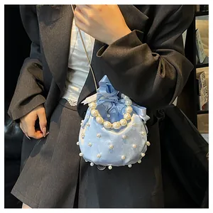 Detail der hellblauen Satin-Beuteltasche mit Perlen, Schleife und Ketten-Schultergurt