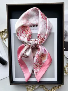 Primo piano di un foulard in seta rosa e crema con motivi floreali su una rivista