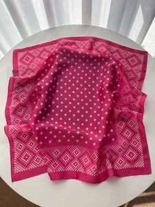 Close-up of pink silk-like square scarf with white polka dots and geometric borders
