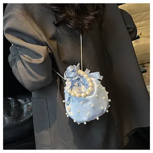 Detail der hellblauen Satin-Beuteltasche mit weißen Perlen und eleganter Schleife
