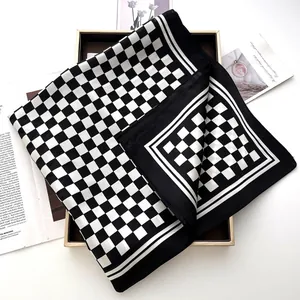 Elegant black and white checkerboard silk scarf on a luxury decorative gold tray