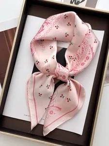 Detail of pink silk square scarf with red cherry prints and paisley patterns in a gift box