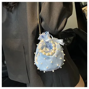Detail der hellblauen Satin-Beuteltasche mit Perlengriffen und Kordelzugverschluss