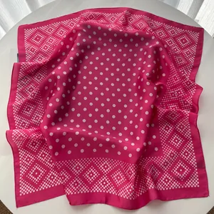 Macro detail of rose pink silk square scarf with white polka dots and geometric patterns