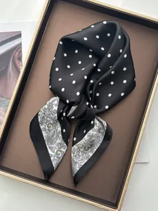 Detail eines Seidenschals mit Paisleymuster und Punkten in einem goldenen Tablett