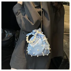 Detail der hellblauen Satin-Beuteltasche mit Perlenverzierung und goldener Kette
