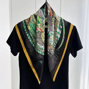 Detail of leaf and feather print silk square scarf elegantly draped on black fabric