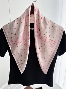 Detail of pink silk square scarf featuring red cherry and paisley patterns on black shirt