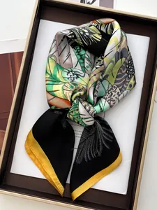 Detail of silk square scarf with tropical leaf print and yellow hem in a gift box