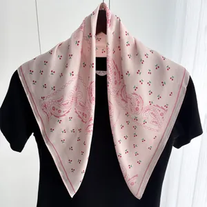 Detail of pink silk scarf with cherry and paisley print styled on a black garment