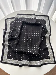 Detail eines Seidenschals mit schwarz-weißen Punkten und Paisley-Mustern auf Satin