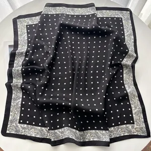 Detail eines Seidenschals mit schwarz-weißen Punkten und Paisley-Muster auf Seidentextur