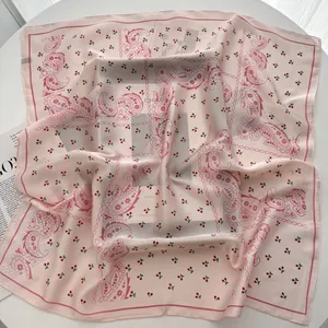 Detail of pink floral silk square scarf with cherry and paisley patterns on magazine