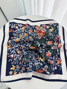 Détail d'un foulard en soie bleu marine avec motifs de fleurs et papillons colorés