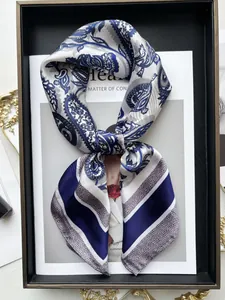 Détail d'un foulard en soie bleu et blanc avec motif paisley sur un plateau élégant