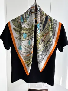 Detailed close-up of a leaf print silk scarf featuring orange borders on a black background