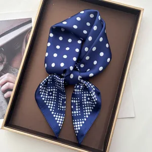 Navy blue polka dot silk-feel scarf with geometric patterns elegantly folded on a tray