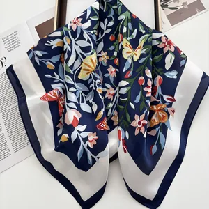 Détail du foulard en soie avec imprimé floral et papillon et texture satinée lisse