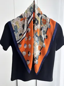 Dettaglio di un foulard in seta arancione con motivi di gatti carini e bordi blu scuro
