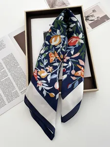 Détail d'un foulard bleu foncé à fleurs et papillons orange dans un coffret cadeau élégant