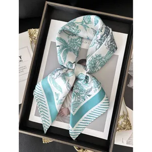 Elegant silk-like square scarf with teal floral patterns in a luxury gift box display