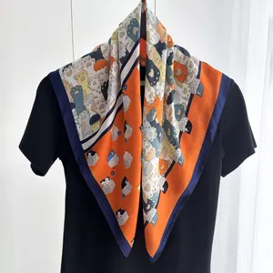Dettaglio di un foulard in seta con stampe di gatti giocosi e bordo arancione