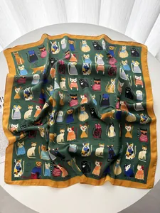Dettaglio di un foulard in seta con motivi di gatti e bordo giallo senape su tavolo