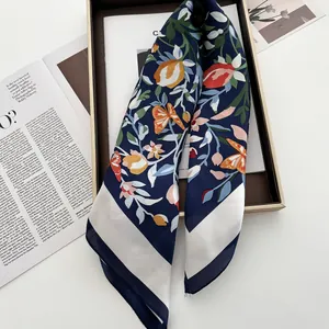 Détail d'un foulard en soie aux motifs de fleurs et papillons dans un coffret cadeau