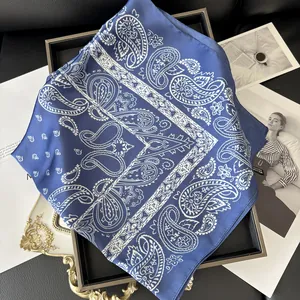 Gros plan détaillé de l'écharpe en soie bleu foncé avec motif paisley blanc sur plateau