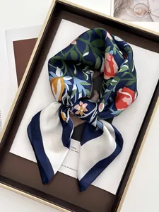 Vue détaillée d'un foulard en soie fleurie avec bordure blanche sur un plateau élégant