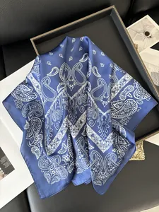 Détail d'un foulard en soie bleu foncé avec motif paisley blanc sur plateau