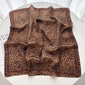 Vista dettagliata del foulard quadrato in seta leopardata con bordi marroni a contrasto