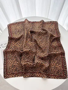 Dettaglio di un foulard quadrato in seta con stampa leopardata e bordo a contrasto