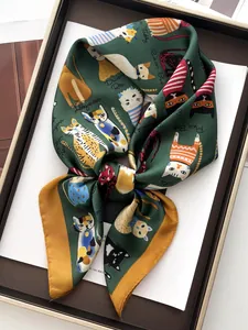 Dettaglio di un foulard in seta verde con illustrazioni di gatti in una scatola regalo