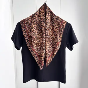 Dettaglio di un foulard in seta con stampa leopardata classica ed eleganti bordi rosso scuro