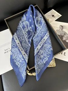 Détail d'un foulard en soie bleu marine à motifs paisley avec accessoires vintage