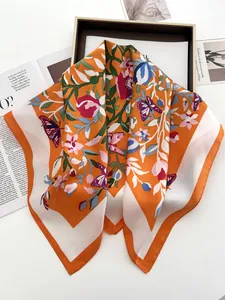 Détail d'un foulard en soie orange avec motifs floraux et papillons à texture brillante